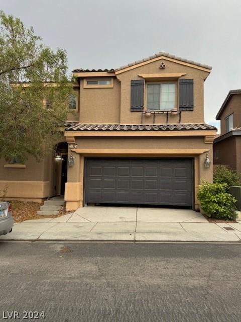 traditional-style home featuring a garage, concrete driveway, a tiled roof, and stucco siding