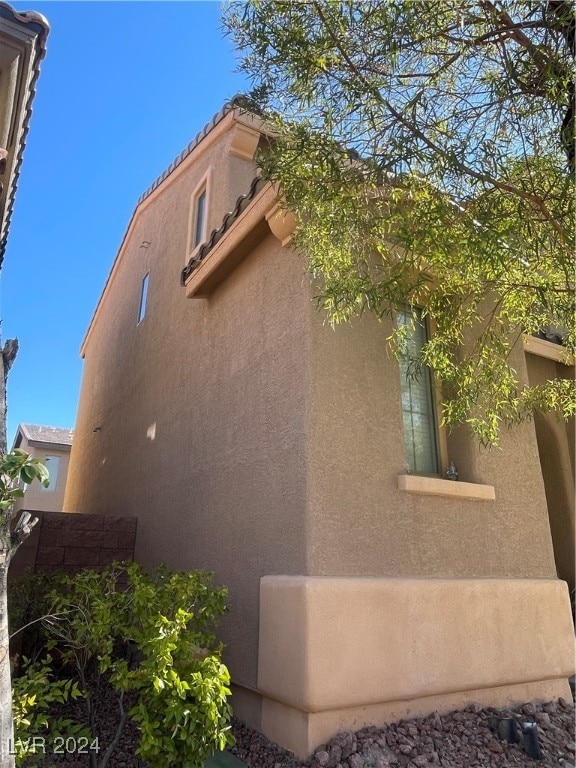 view of side of home featuring a tile roof and stucco siding