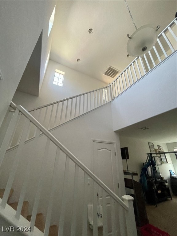 stairs with a high ceiling and visible vents