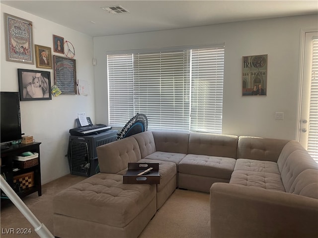 living room with a wealth of natural light, visible vents, and light colored carpet