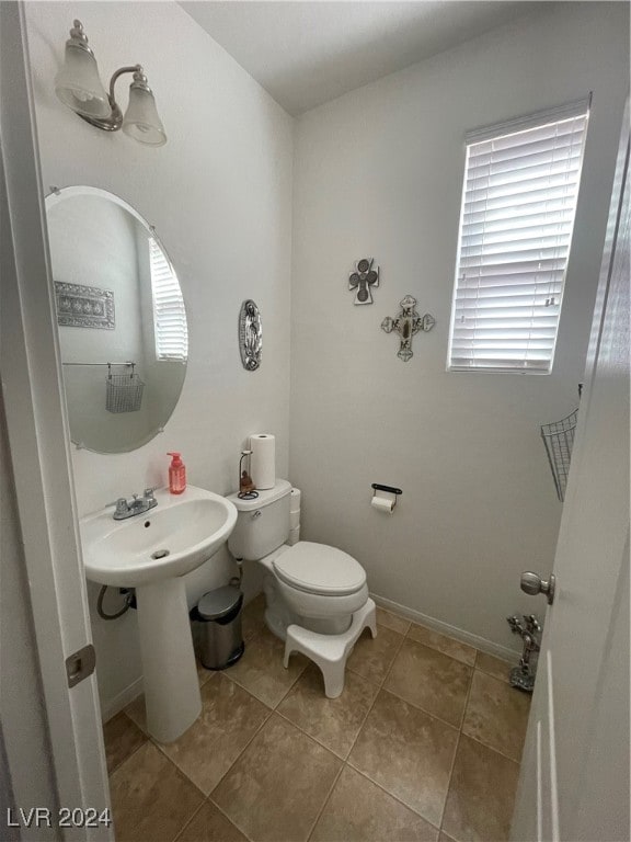 bathroom featuring a healthy amount of sunlight, tile patterned flooring, toilet, and baseboards