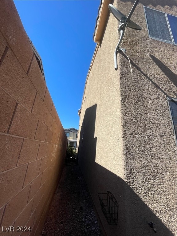 view of side of home featuring fence and stucco siding