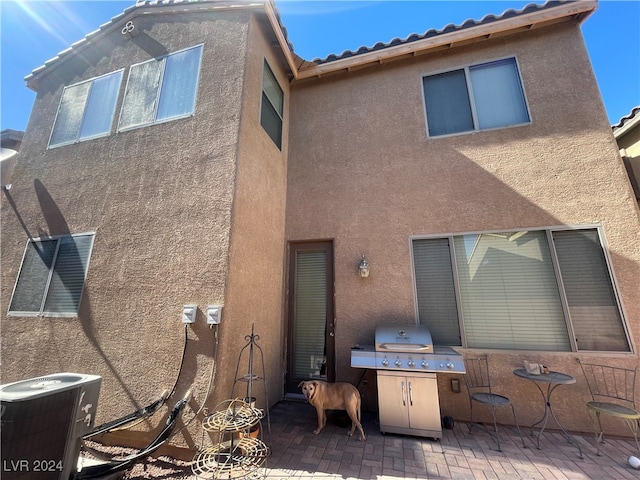 back of property featuring a patio area, a tile roof, central AC unit, and stucco siding