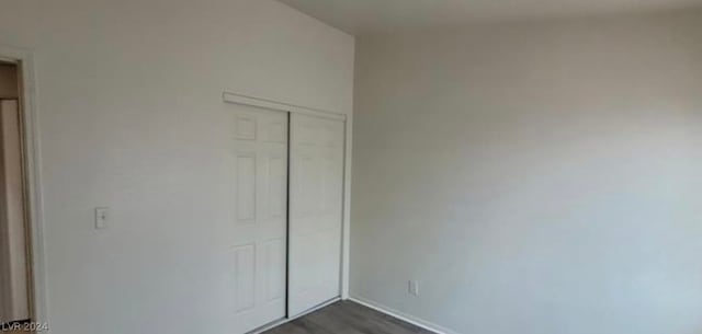 unfurnished bedroom featuring dark hardwood / wood-style flooring and a closet