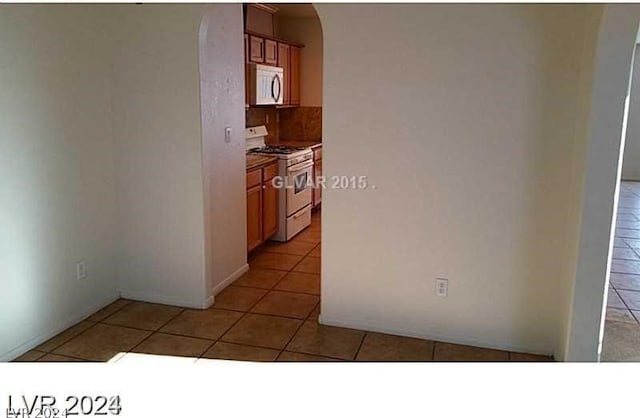 kitchen with white gas stove and light tile patterned floors