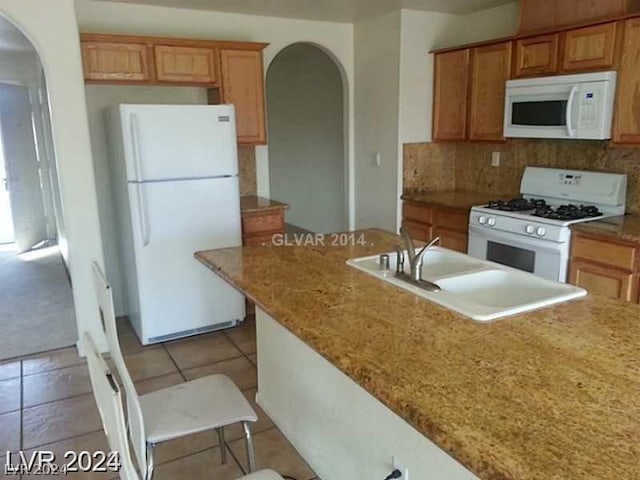 kitchen with white appliances, sink, light stone counters, light tile patterned floors, and backsplash