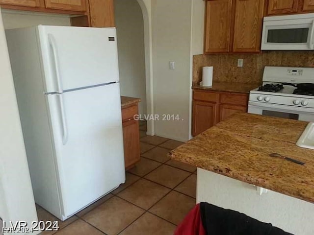 kitchen with decorative backsplash, white appliances, and light tile patterned floors