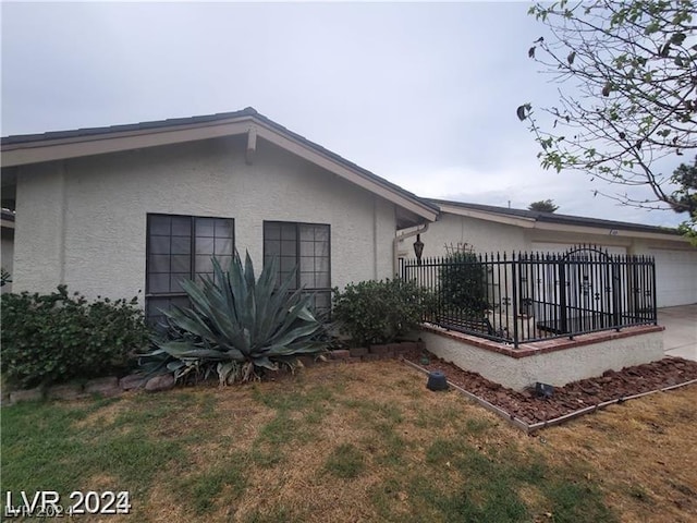 view of side of property with a garage and a lawn