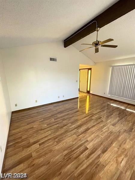 unfurnished room with lofted ceiling with beams, hardwood / wood-style flooring, and a textured ceiling