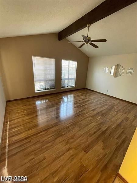 empty room featuring hardwood / wood-style floors, a textured ceiling, lofted ceiling with beams, and ceiling fan