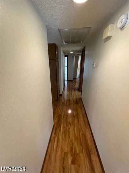 hall featuring wood-type flooring and a textured ceiling