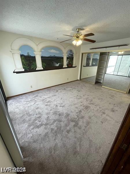 unfurnished bedroom with ceiling fan, carpet floors, and a textured ceiling