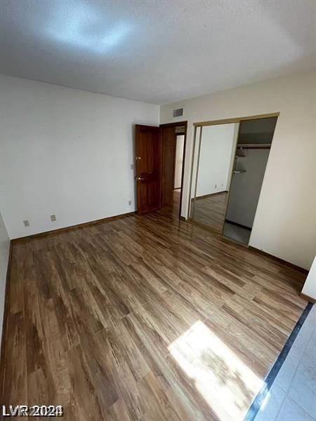 unfurnished bedroom featuring hardwood / wood-style floors, a closet, and a textured ceiling