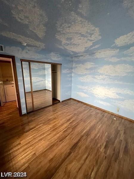 unfurnished bedroom featuring hardwood / wood-style floors, a textured ceiling, and washer and clothes dryer