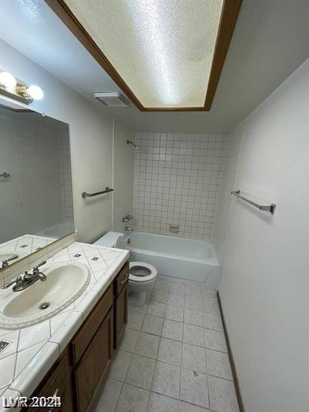 full bathroom with tile patterned floors, toilet, a textured ceiling, vanity, and tiled shower / bath combo