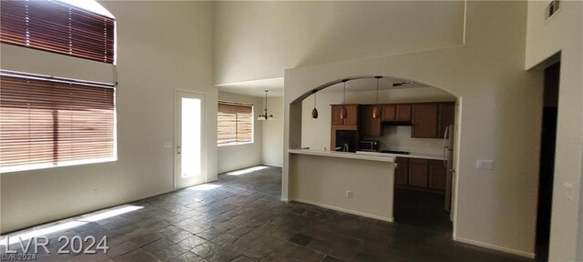 kitchen with pendant lighting, fridge, kitchen peninsula, and a high ceiling