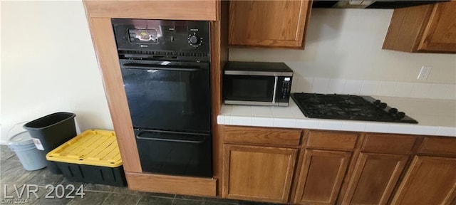 kitchen featuring tile countertops, ventilation hood, and black appliances