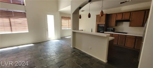 kitchen featuring pendant lighting, black appliances, kitchen peninsula, and a wealth of natural light