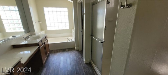 bathroom with wood-type flooring, separate shower and tub, and vanity