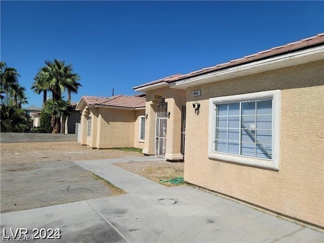 exterior space featuring stucco siding, a tiled roof, and a patio