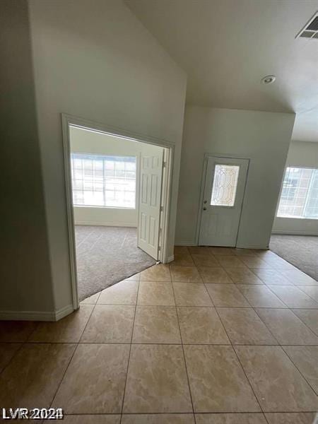 foyer with light carpet, visible vents, baseboards, and light tile patterned floors