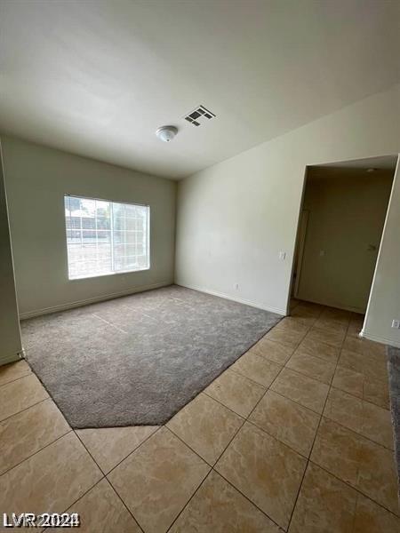 tiled empty room with visible vents and carpet