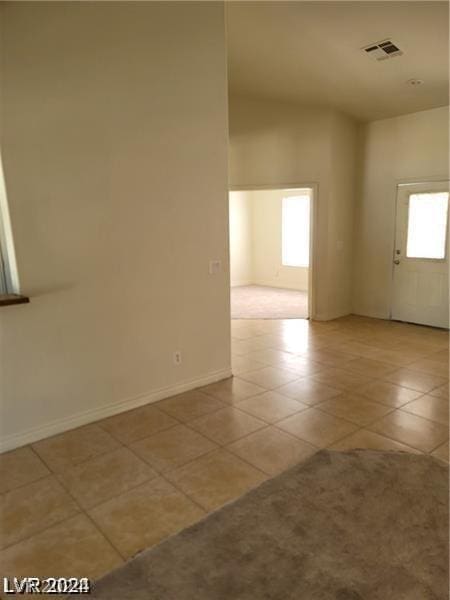 tiled spare room with visible vents, a healthy amount of sunlight, and baseboards