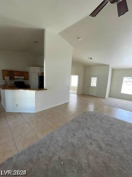 unfurnished living room with lofted ceiling, light tile patterned floors, and ceiling fan