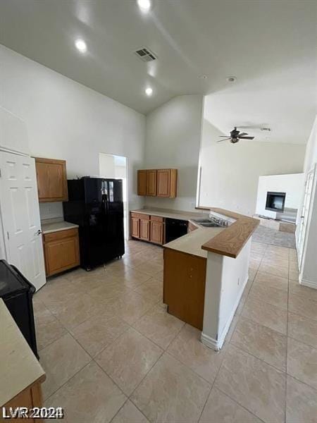 kitchen featuring visible vents, brown cabinets, freestanding refrigerator, a peninsula, and a fireplace