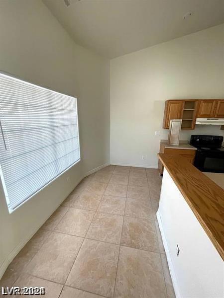 kitchen featuring light tile patterned floors, brown cabinetry, open shelves, black electric range, and under cabinet range hood