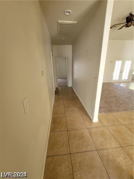 hallway with light tile patterned floors, light carpet, and baseboards