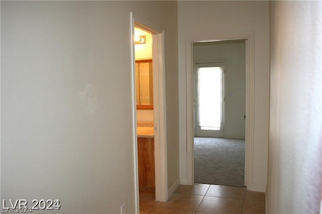 hallway with light tile patterned floors and light colored carpet