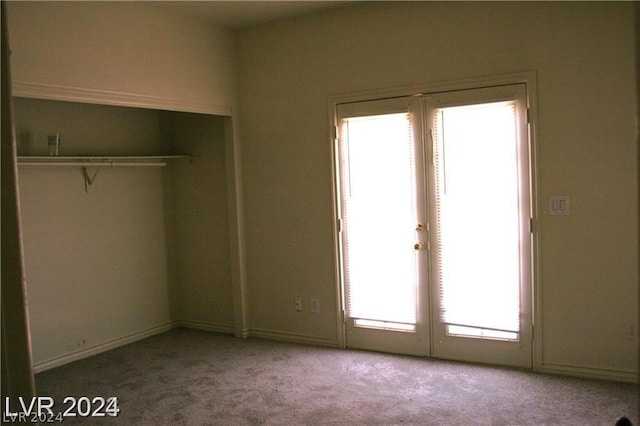 unfurnished bedroom featuring french doors, a closet, and carpet flooring