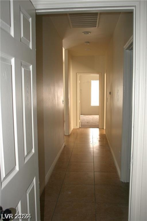 corridor with tile patterned flooring, baseboards, and visible vents