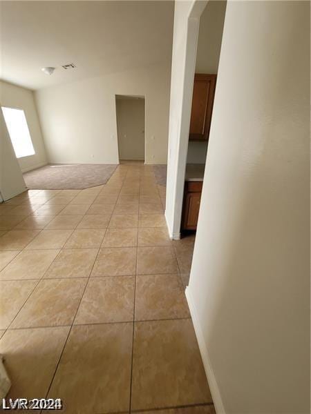 empty room with light tile patterned floors, baseboards, and visible vents