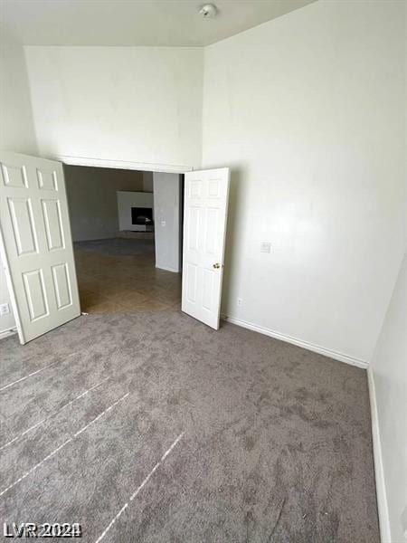 spare room featuring baseboards, carpet, and high vaulted ceiling