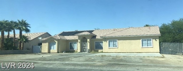 view of front of property featuring solar panels, fence, and stucco siding