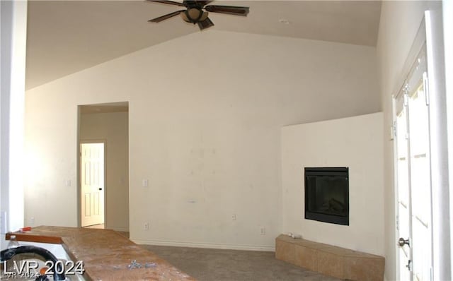 unfurnished living room featuring a glass covered fireplace, vaulted ceiling, carpet, and ceiling fan