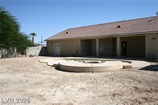 rear view of property featuring stucco siding, french doors, and a patio