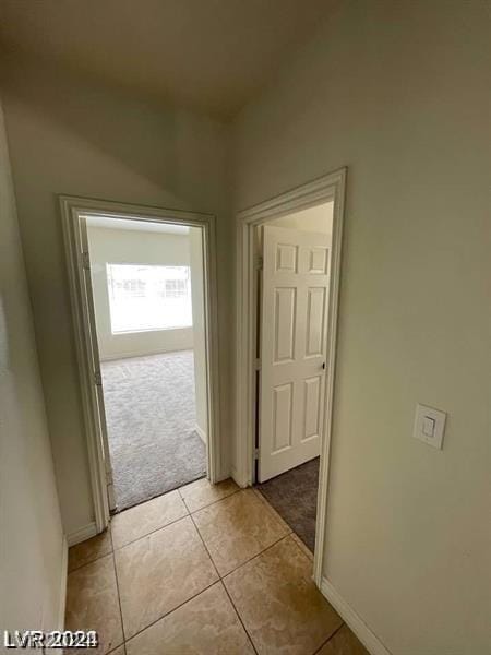 hallway featuring light tile patterned flooring, light carpet, and baseboards