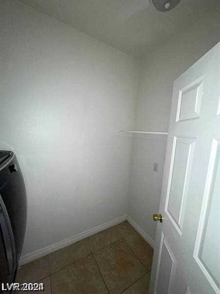 clothes washing area with light tile patterned floors, laundry area, washer / clothes dryer, and baseboards