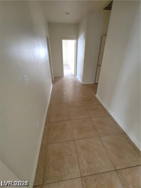 hall featuring light tile patterned floors, visible vents, and baseboards