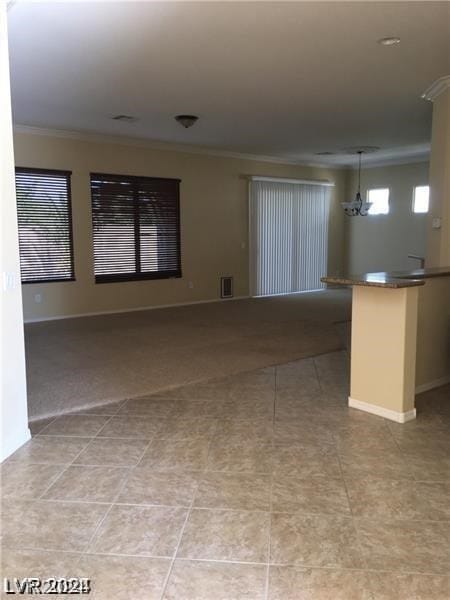 interior space with an inviting chandelier, crown molding, and light tile patterned floors