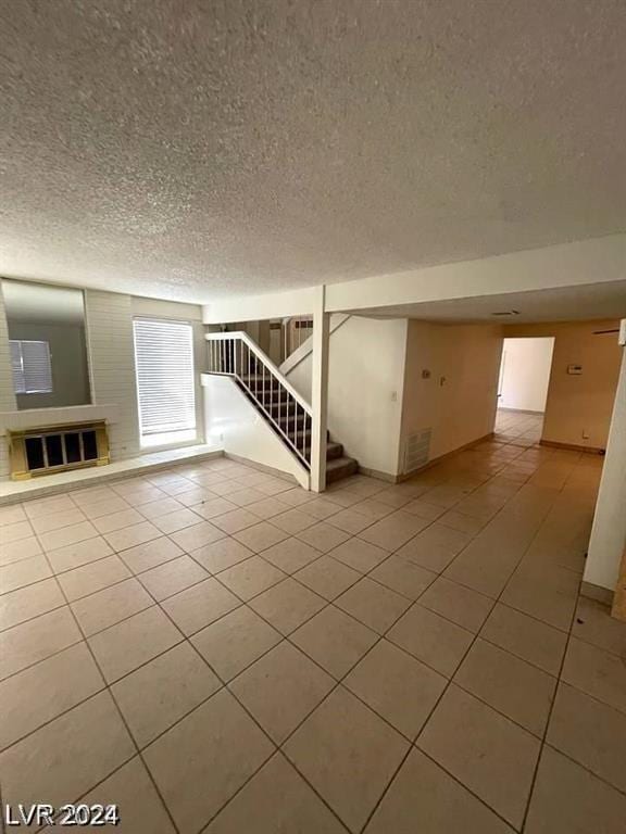 unfurnished living room with a textured ceiling and light tile patterned floors