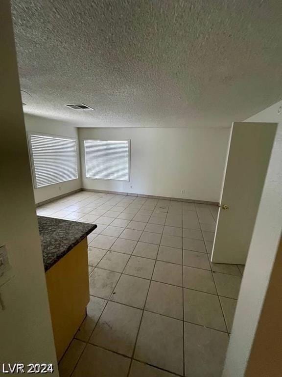 spare room with a textured ceiling and light tile patterned floors