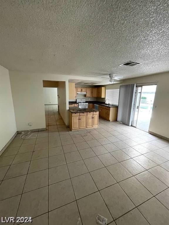 kitchen featuring ceiling fan, white gas range, a textured ceiling, and light tile patterned floors