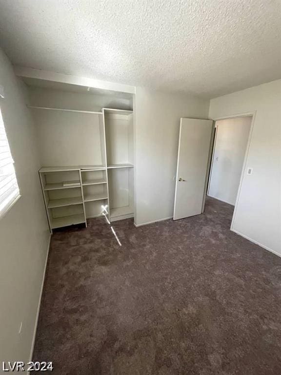 unfurnished bedroom featuring dark carpet, a closet, and a textured ceiling