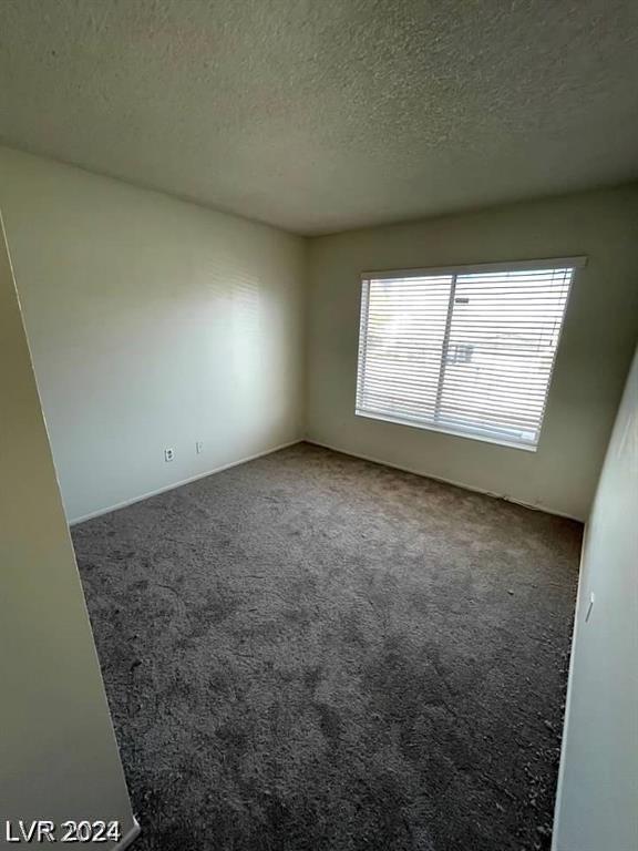 carpeted empty room featuring a textured ceiling