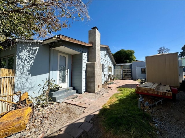 view of side of home with entry steps and a chimney