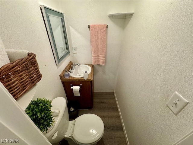 bathroom with a textured wall, vanity, toilet, and baseboards